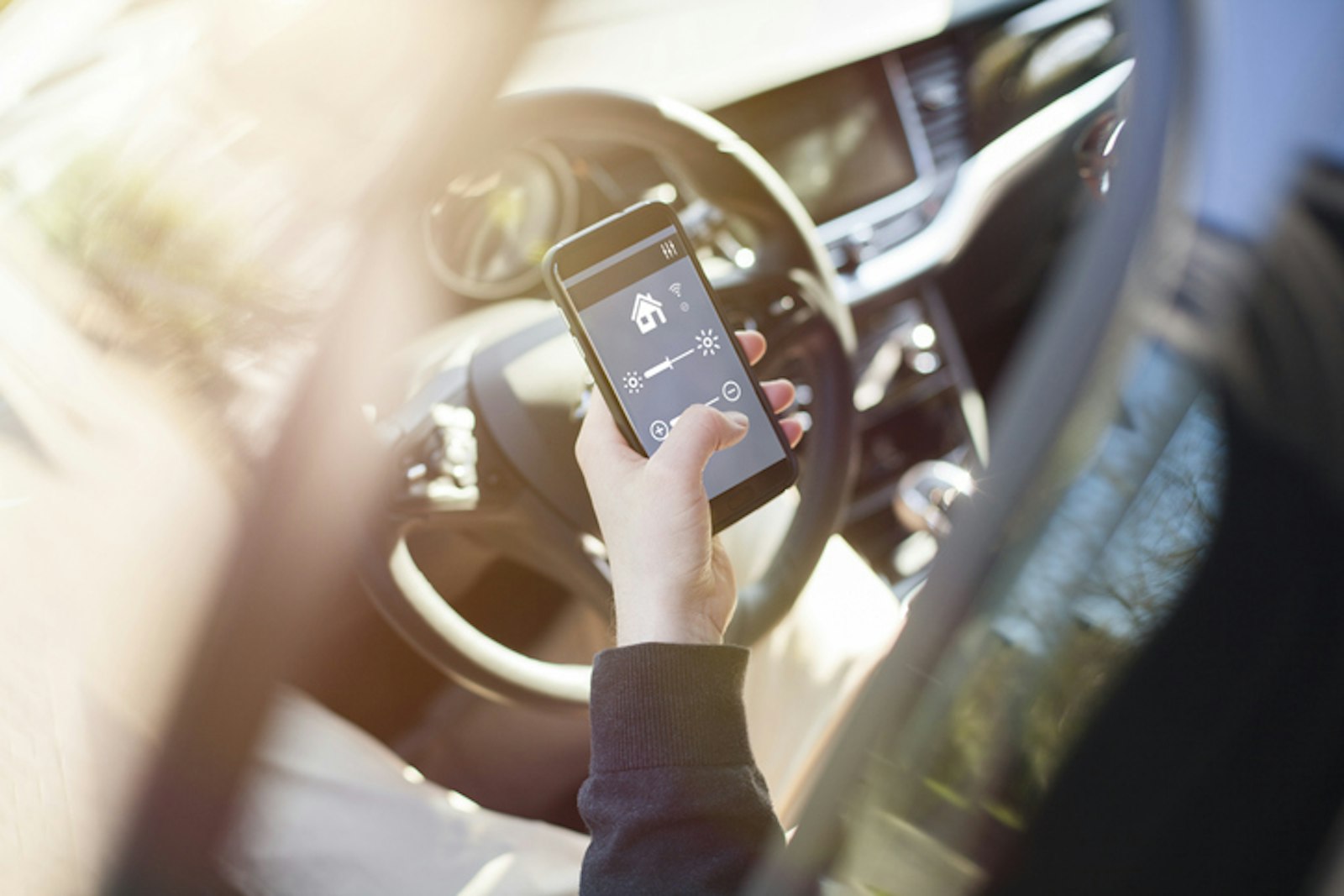 Smartpohne Auto Person sitzt in stehendem Auto und recherchiert am Smartphone