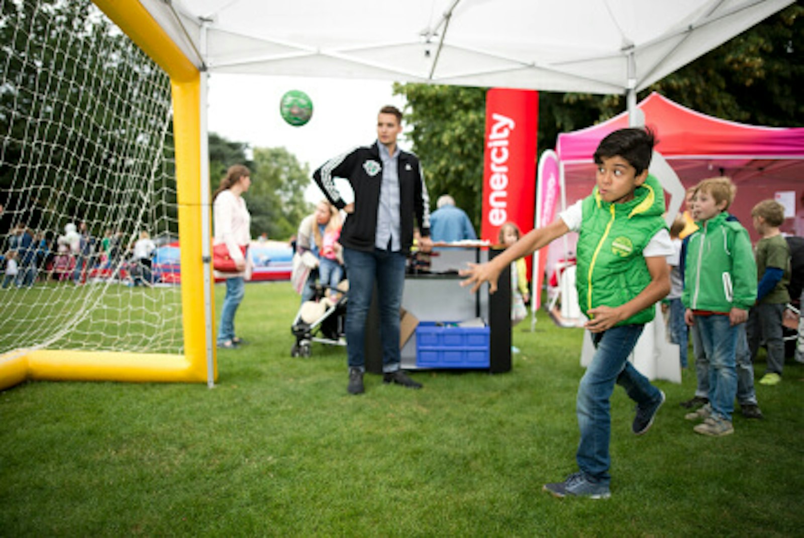 wissenswert-rendezvous-hannover.jpg Rendezvous. Dieses Bild zeigt einen Kunden, der einen Ball auf ein Tor wirft. Im Hintergrund sieht man einen Mann, der aufpasst und weitere Jungs.