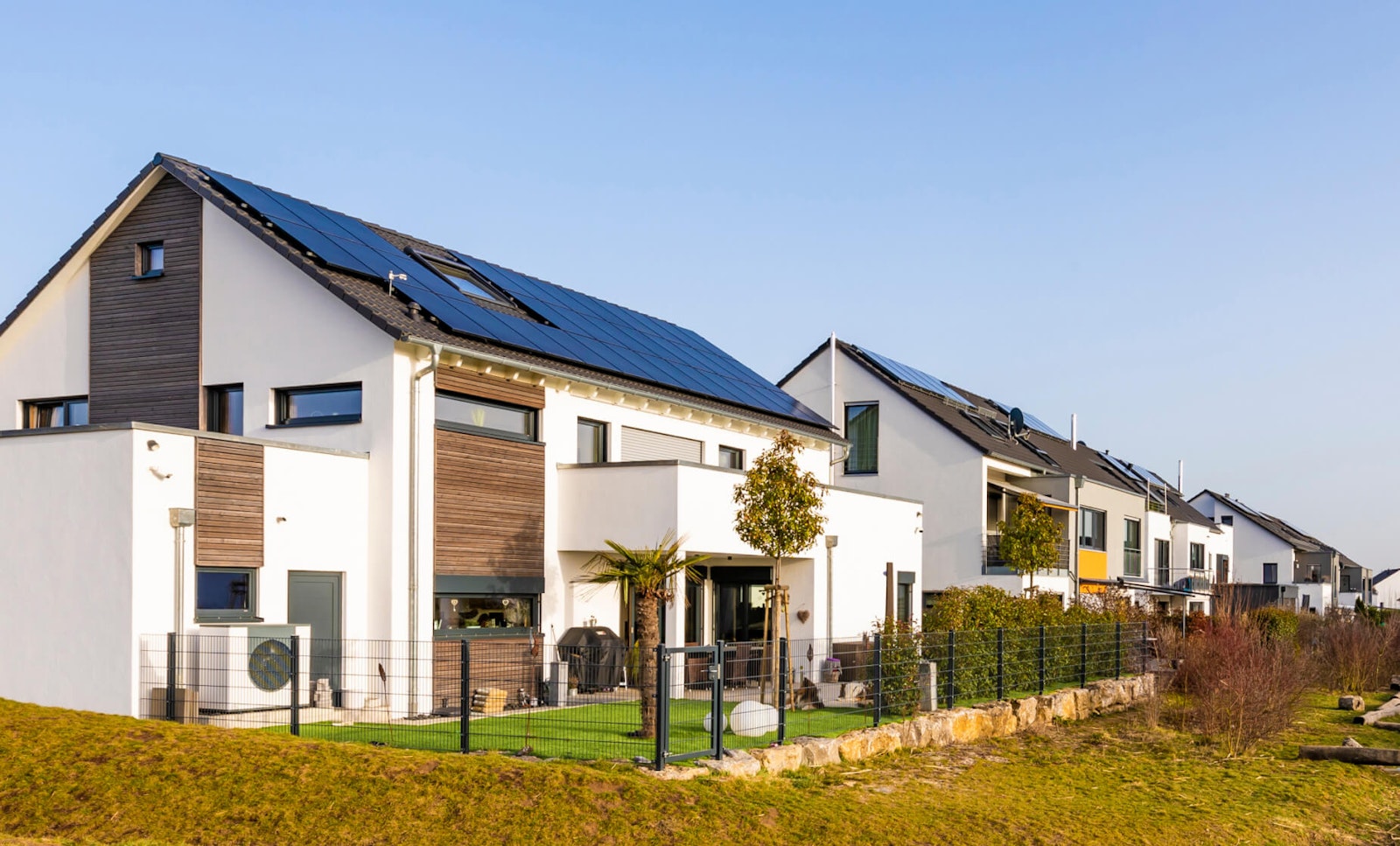 Investition PV-Anlage Blick über eine Reihenhaussiedlung, in der alle Häuser mit einer PV-Anlage auf dem Dach ausgestattet sind.