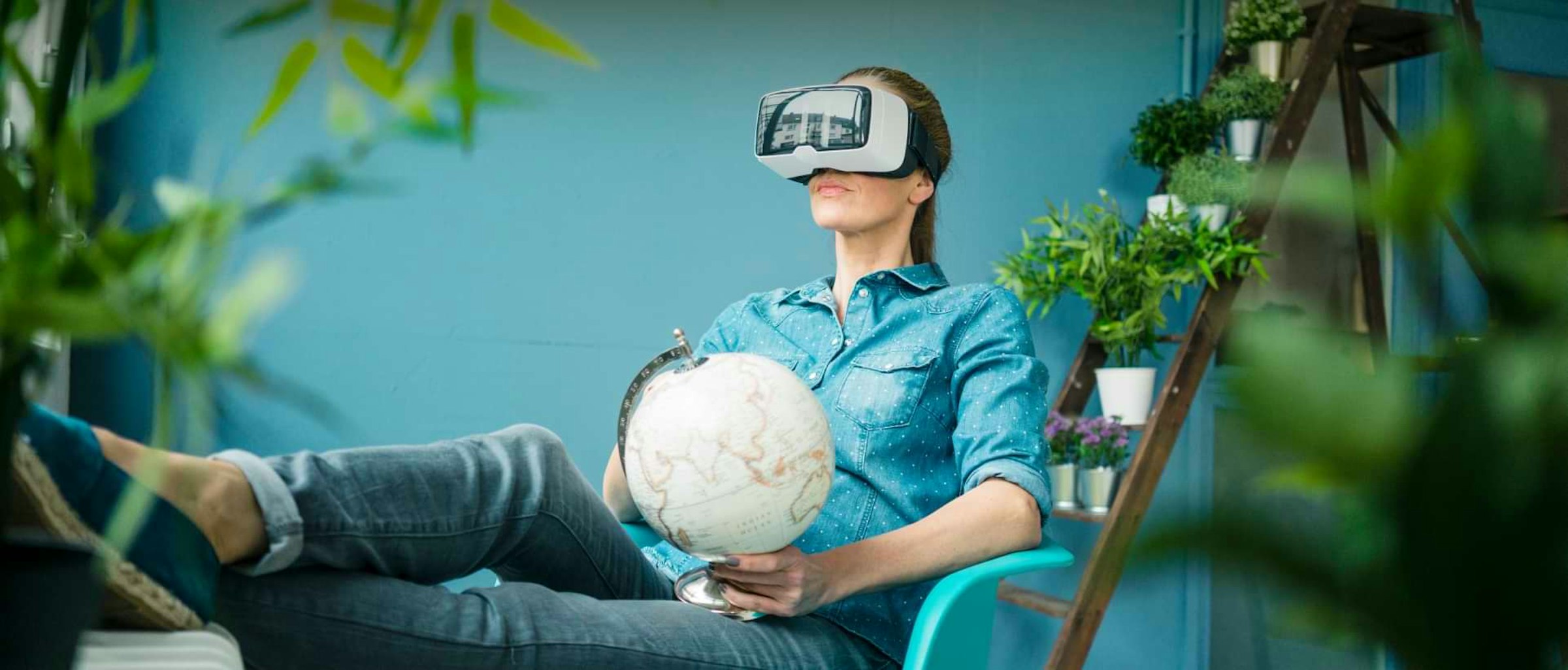 Nachhaltige Wohnkonzepte der Zukunft Wohnkonzepte der Zukunft: Das Bild zeigt eine Frau zuhause im Sessel mit einer Virtual Reality Brille auf dem Kopf.