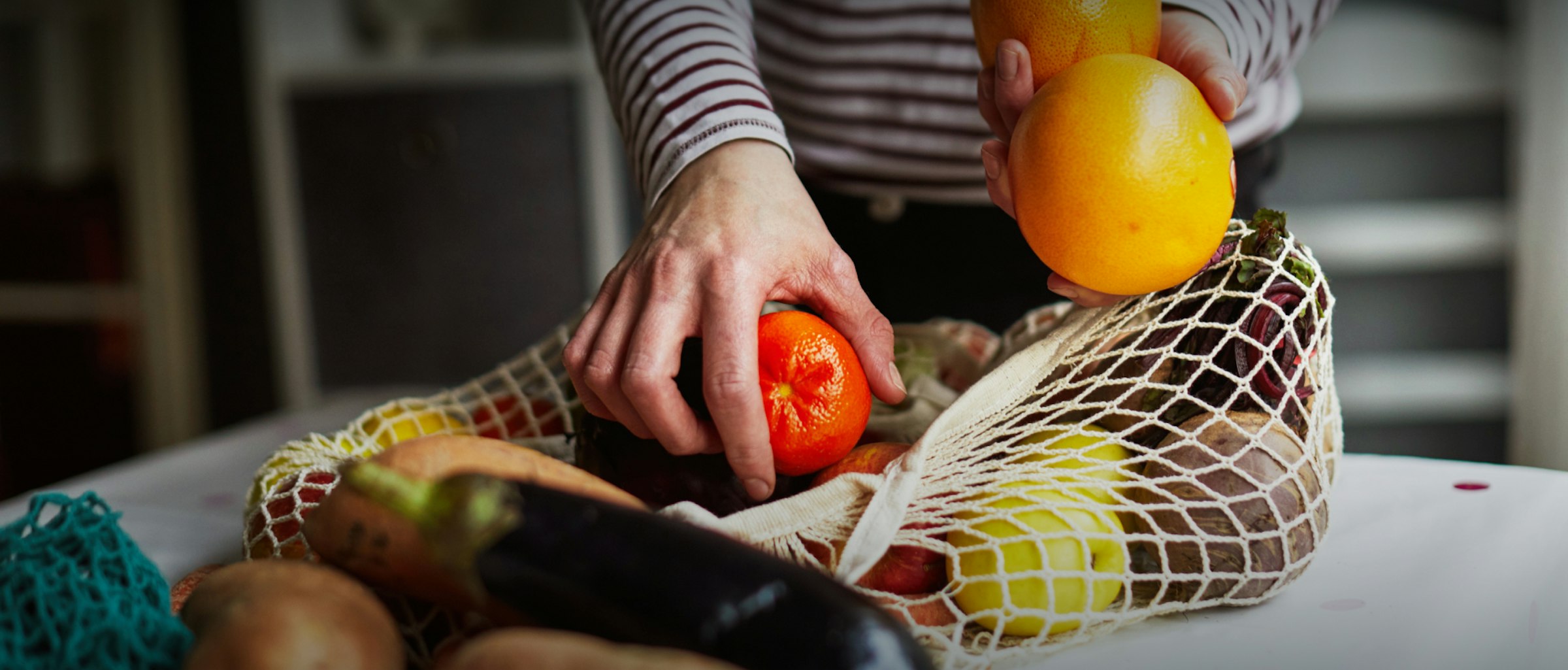 Plastik vermeiden. Dieses Bild zeigt einen Netzbeutel aus Stoff, in dem verschiedenes Obst und Gemüse ist.