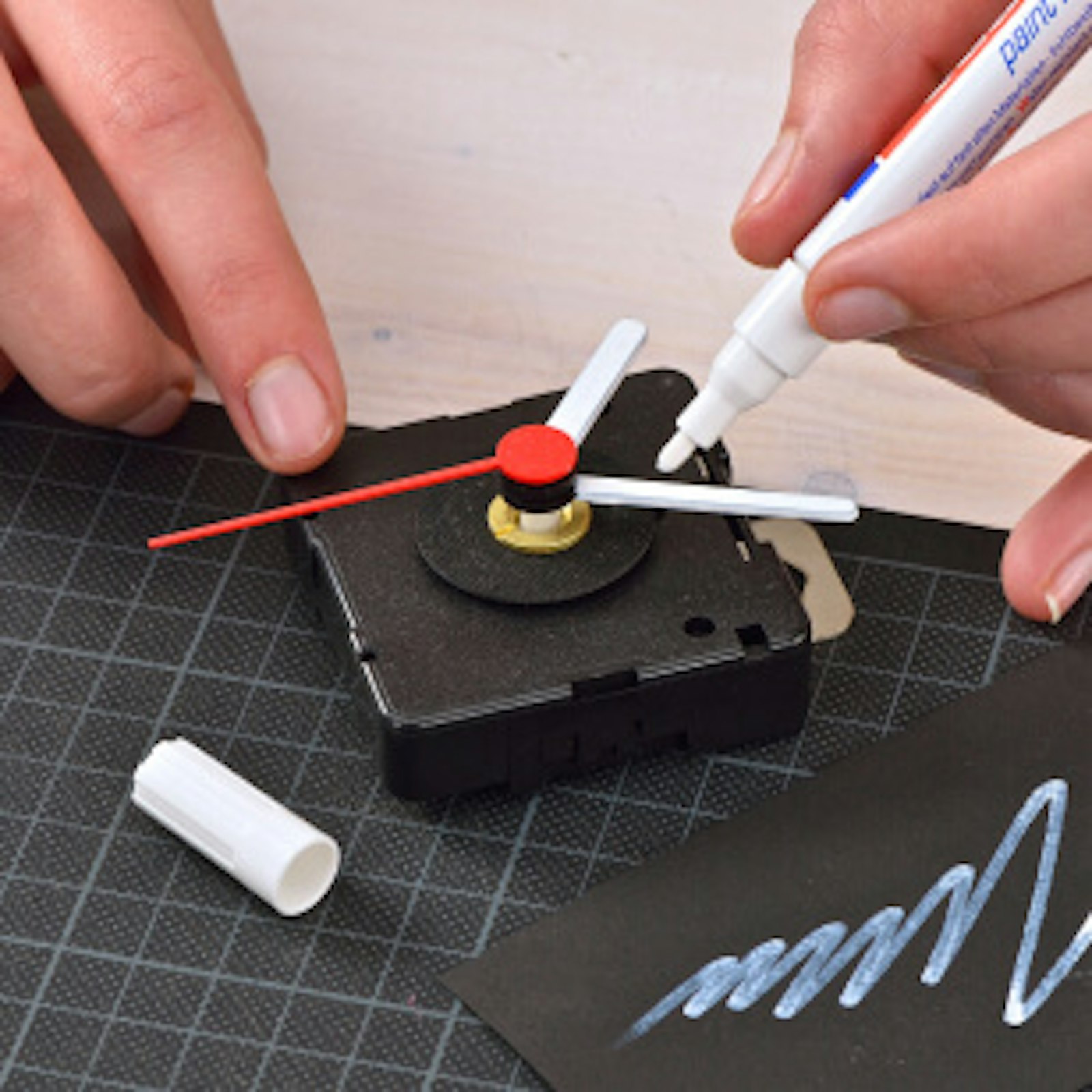 diy-uhr-beschriften.jpg Schritt 2: Das Bild zeigt, wie Minutenzeiger und Stundenzeiger der Uhr mit einem weißen Edding markiert werden.
