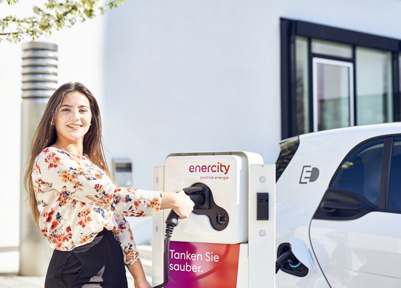 wallbox-lexikon Eine Frau lädt ihr E-Auto an einer Ladestation auf ihrem Stellplatz.