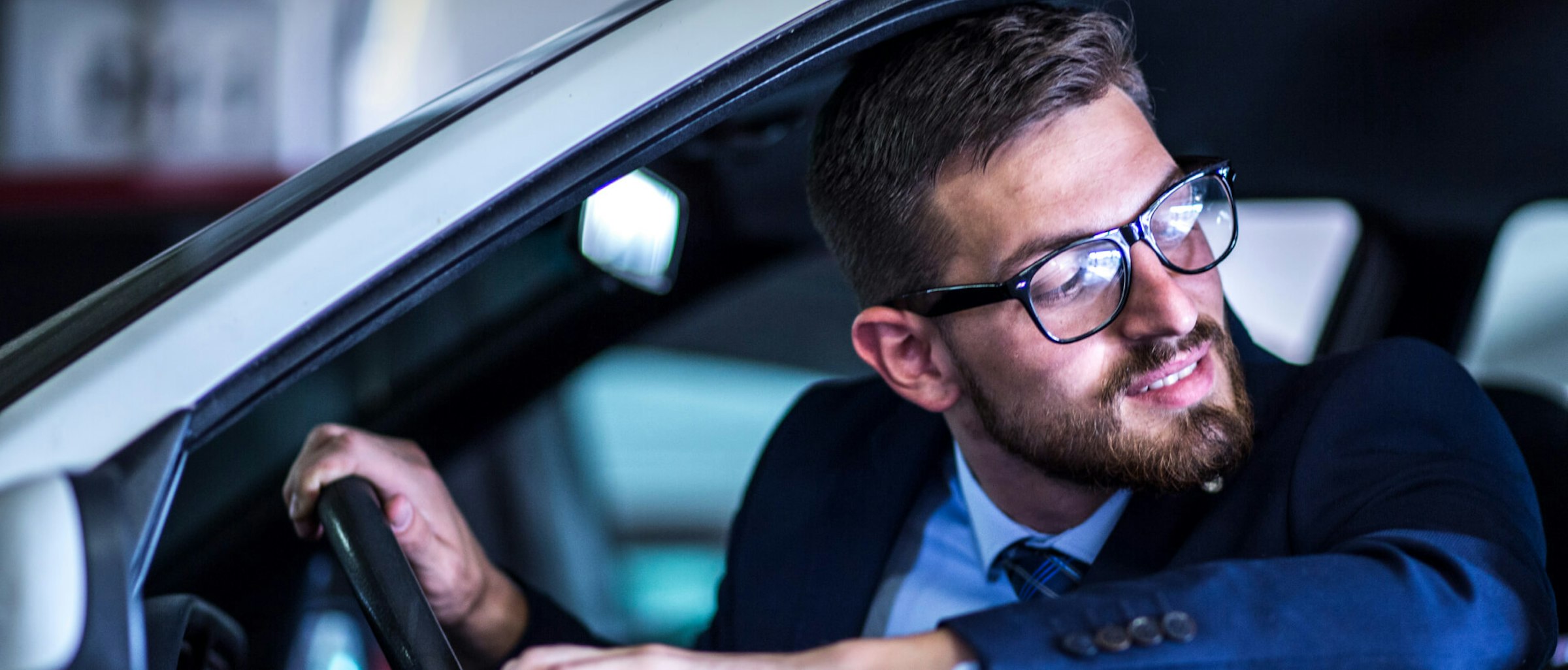 Mann mittleren Alters, der aus dem Fahrerfenster seines Autos nach hinten guckt. Mann mittleren Alters, der aus dem Fahrerfenster seines Autos nach hinten guckt.